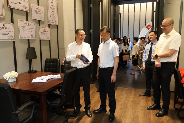广西税务局党委委员、总经济师黄尚书（左二）和米兰milan官方网站党委书记刘子林（左一）在柳州市高校税收普法教育实践站税收普法教育研究室翻阅税法知识读本